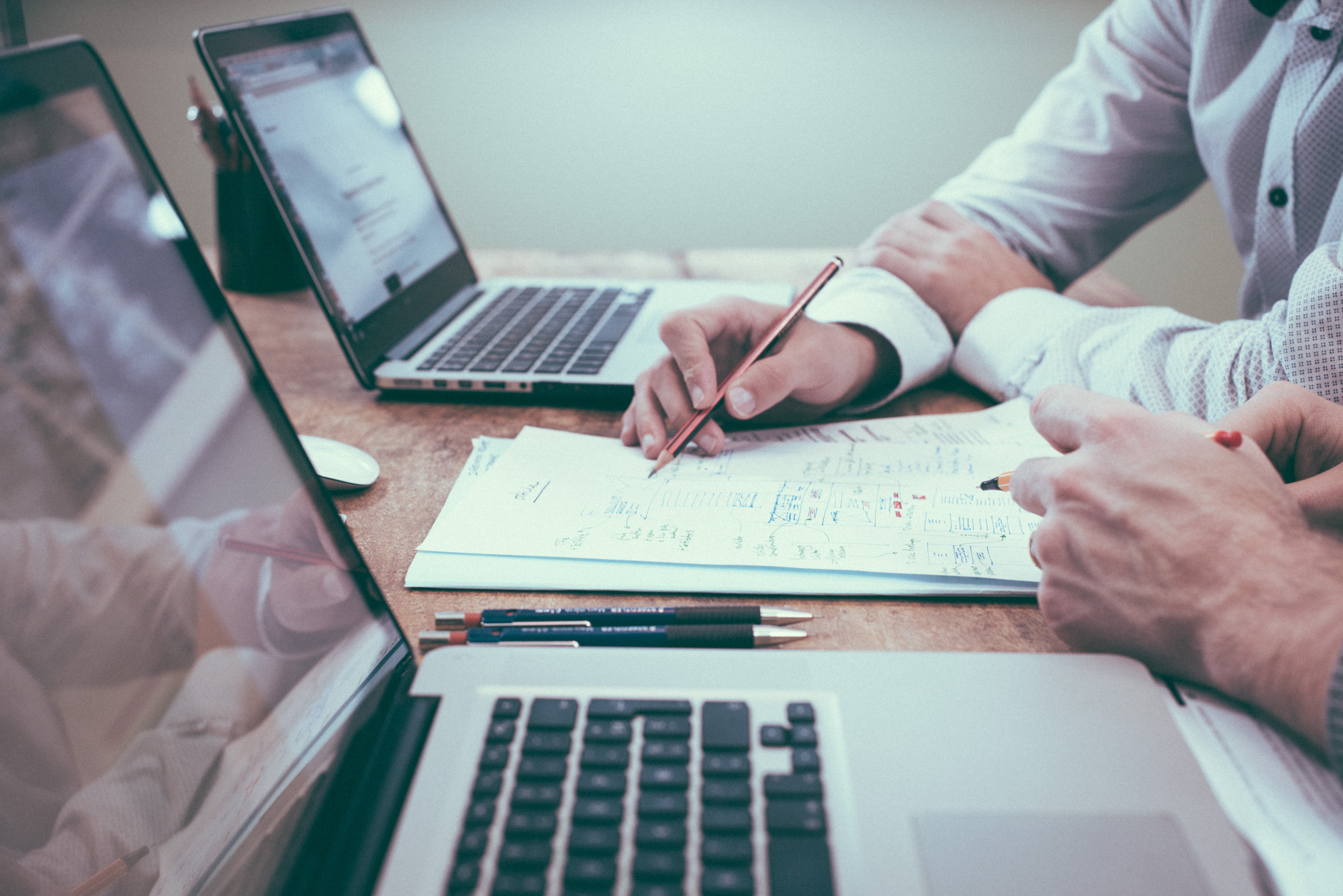 Zwei Kollegen sitzen vor ihren Laptops.